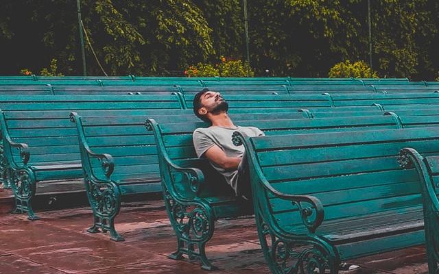 Adult sitting on a bench looking bored