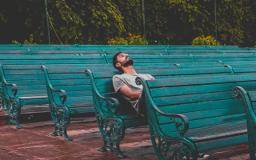 Thumbnail sized: Adult sitting on a bench looking bored
