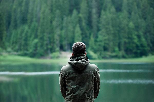 Adult from the back, looking at the lake in the woods
