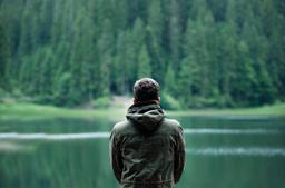 Thumbnail sized: Adult from the back, looking at the lake in the woods