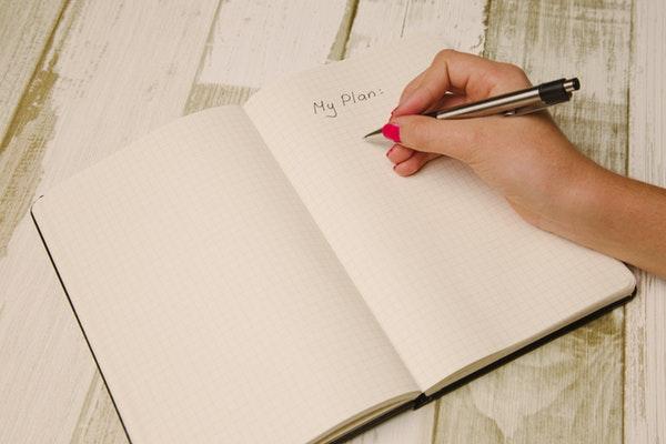 Hand with pen over a journal on desk