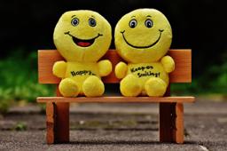 Thumbnail sized: miniature yellow plush gingerbread men sitting on tiny park bench