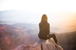 Thumbnail sized: Woman sitting on rock peak facing away